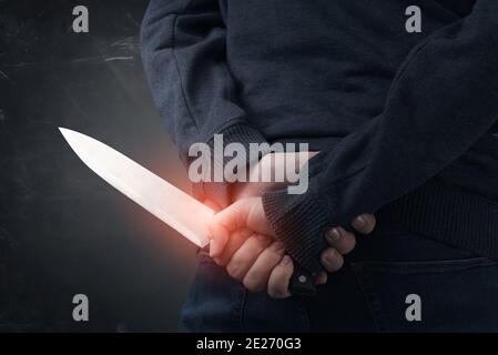 Close-up on the murderer holding the murder weapon. Man with a knife in his hand Stock Photo