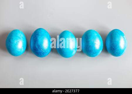 Row of five blue Easter eggs on grey background Stock Photo