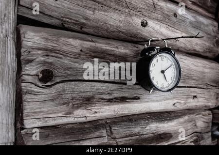 A bell hanging on a thin wooden stick stuck in an old log house Stock Photo
