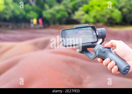Mauritius, Africa - Jan 2021: An unidentified man holding gimbal a camera stabilizer . Man holding gimbal stabilizer outdoor. Gimbal Operator with Stock Photo