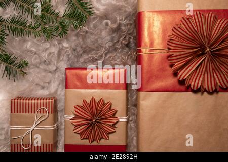 Arranged Handmade Decorative Gift Boxes under the Christmas tree on Woolen Fur and Fir Branch. Merry Christmas Background And Happy Holiday Greeting C Stock Photo
