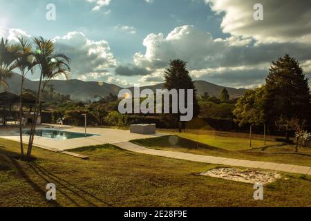 Photograph at sunset of country side landscape with mountains, trees and a pool, with lens flare. Stock Photo