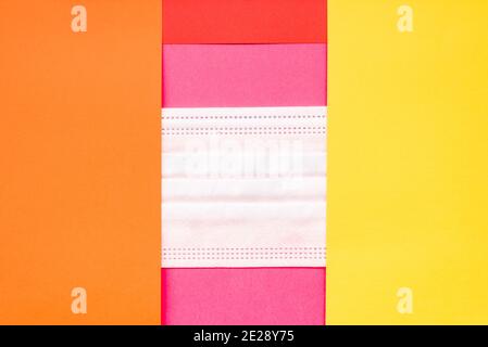 A sanitary mask between papers of various colors, background to fill. Stock Photo