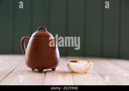 Healthy beverage. Clay teapot and onyx stone cup on white wooden table side view copy space. Minimalist style still life with natural lighting side vi Stock Photo