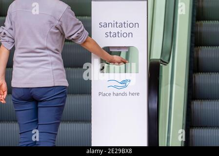 Close-up view of woman sanitizing her hands at sanitation station Stock Photo