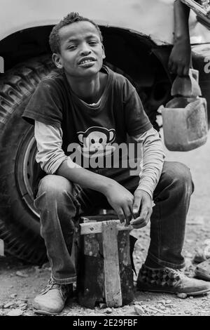 ADDIS ABABA, ETHIOPIA - Jan 05, 2021: Addis Ababa, Ethiopia, January 27, 2014, Young teenager working as a shoe shine boy on the street, looking strai Stock Photo