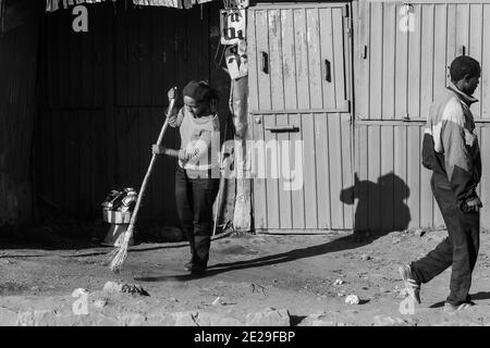 ADDIS ABABA, ETHIOPIA - Jan 05, 2021: Addis Ababa, Ethiopia, January 30, 2014, Young woman sweeping the front entrance to her informal store in the ea Stock Photo