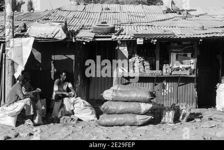 ADDIS ABABA, ETHIOPIA - Jan 05, 2021: Addis Ababa, Ethiopia, January 30, 2014, People sitting outside small colorful grocery shops on a side street Stock Photo