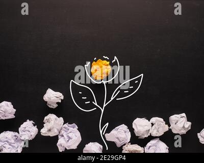 Concept for new ideas, yellow crumpled paper grows up as a flower, creativity and wisdom. Stock Photo