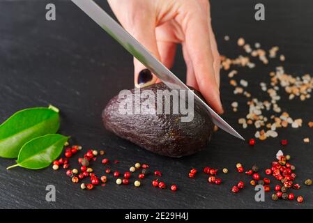 chef slicing the avocado close-up on a black board Stock Photo