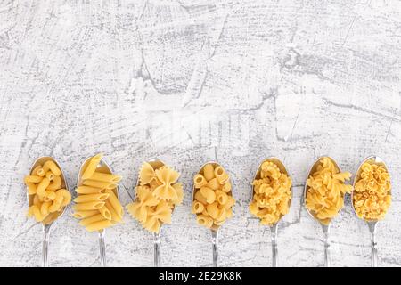 Italian foods concept and menu design. Various kind of Pasta Farfalle, Pasta A Riso, Orecchiette Pugliesi, Gnocco Sardo and Farfalle in spoons setup o Stock Photo