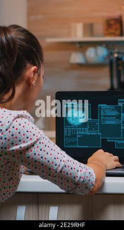 Woman hacker coding html and programming on screen laptop working from home in midnight. Programmer writing a dangerous malware for cyber attacks using performance device during midnight. Stock Photo