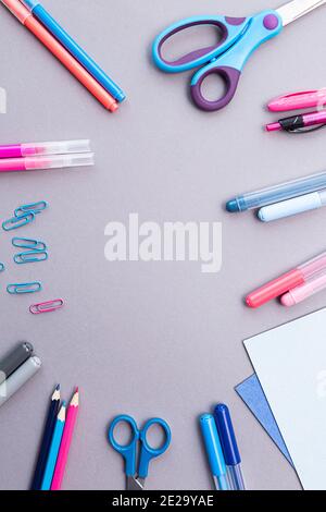 Various stationery in pink and blue colors, blank sheets of paper, on a gray background with copy space. Flat lay with pencils, scissors, pens, paper Stock Photo
