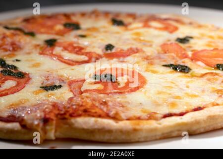 Close up of pizza margarita with pesto sauce on wooden board. Blur foreground, macro Stock Photo