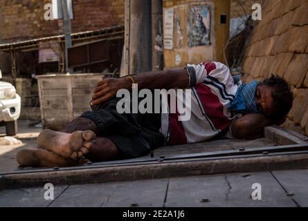 Jaisalmer, Rajasthan / India - November 1 2020 : middle aged man sleeps on a hand cart covering his face with handkerchief from corona virus pandemic, Stock Photo