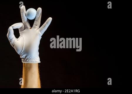 Player wearing a golf glove holding a golf ball in his fingers. Stock Photo