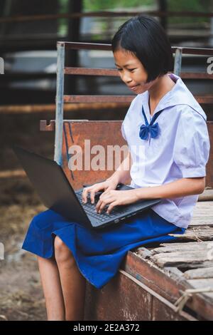 Asian uniform student girl using computer notebook with smile and happy Stock Photo