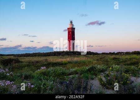 Lighthouse standing on the Dutch coast with a dramatic. and colorful dusk or dawn sky behind it. High quality photo Stock Photo