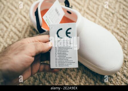 Paris, France - Dec 13, 2020: POV male hand holding paper advertising tag of Crocs at work comfortable shoes with price tag etiquette with instructions for use Stock Photo