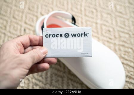 Paris, France - Dec 13, 2020: POV male hand holding paper advertising tag of Crocs at work comfortable shoes with price advertising etiquette Stock Photo