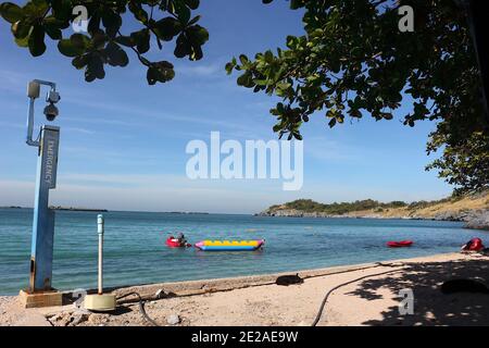 Picture of the view of the sea and sky. There are red scooter boat and yellow banana boat in the foreground. And mountains in the background. There is Stock Photo