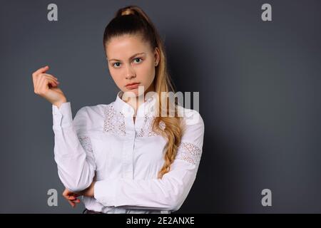 Pensive young business woman looking at the camera and posing on a gray background with blank space. Stock Photo