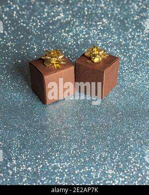 Small gift boxes with gold bow, placed on a shimmering background. Idea of gifts, offers, sales, events. Stock Photo