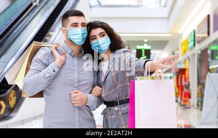 Loving couple in face masks doing shopping in city mall Stock Photo