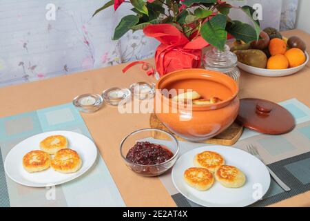 sweet cottage cheese pancakes in a plate and a clay pot, with jam on a server table Delicious cottage cheese dessert. High quality photo Stock Photo