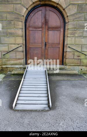 large wooden arched door with ramp for use of wheelchairs or prams covered in frost on a cold winters day Stock Photo