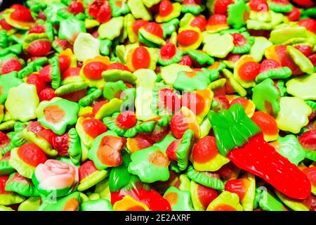 Bright green, yellow, white and red marmalade gummies in the shape of strawberries. Sweet beautiful delicacy made from gel fruit juices. Colorful Stock Photo