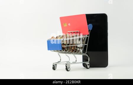 Shopping cart full of coins with a bank credit card and a cell phone.Shopping online spend and save money, financial business concept.Mock up banner t Stock Photo