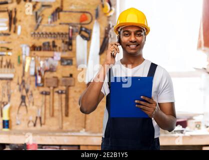indian builder with clipboard calling on cellphone Stock Photo