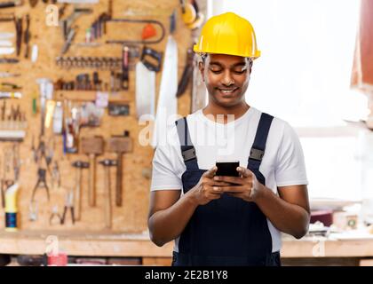 happy indian or builder in helmet using smartphone Stock Photo