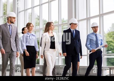 business team in helmets walking along office Stock Photo