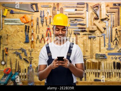 happy indian or builder in helmet using smartphone Stock Photo