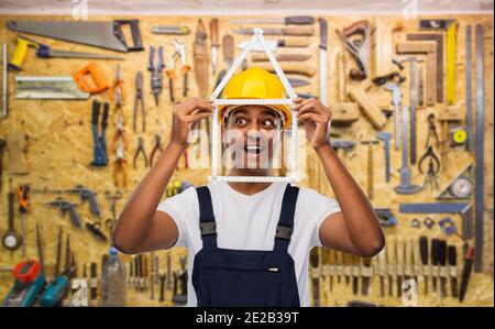 happy indian builder with ruler in shape of home Stock Photo