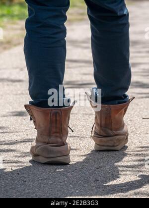 Young person walking in old worn out leather boots Stock Photo