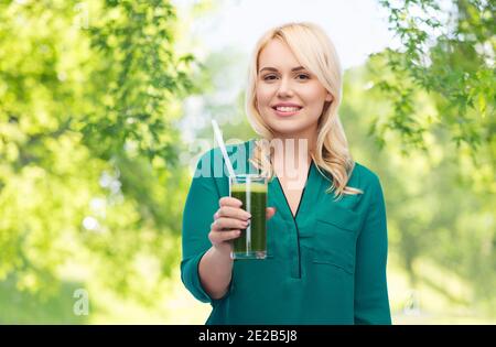 smiling woman drinking vegetable juice or smoothie Stock Photo