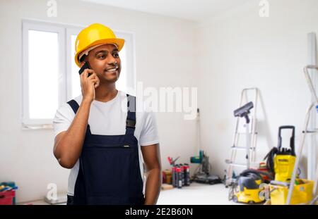 indian builder in helmet calling on smartphone Stock Photo