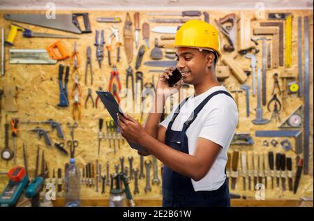 indian builder with clipboard calling on cellphone Stock Photo