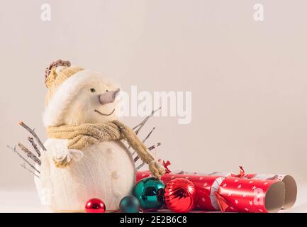 Snowman decoration wearing hat and scarf with baubles and crackers around. January 2021. Stock Photo
