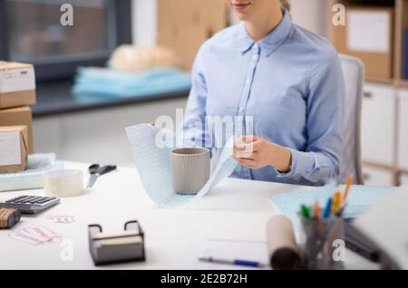 woman packing mug to parcel box at post office Stock Photo