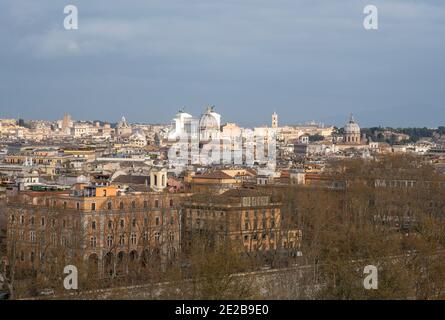 View down over rooftops onto central Rome from Trastevere across the River Tiber. The Vittorio Emanuele II Monument in the centre Stock Photo