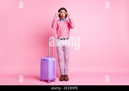Full length photo of funny handsome surprised brunet hair man tourist arms spectacles luggage isolated pink color background Stock Photo