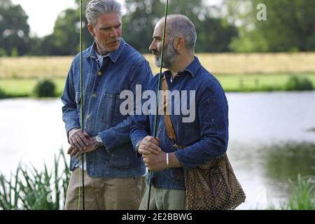 Two male friends fishing and talking together Stock Photo
