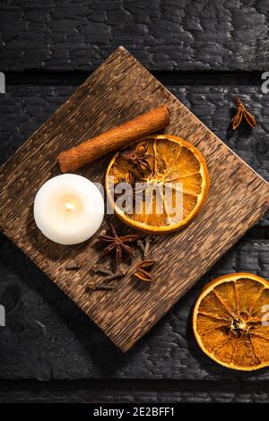 Winter spices concept. Flat lay view of various spices: cinnamon stick, clove, star anise, dried orange slices. Wood plate with seasonal potpourri. Stock Photo