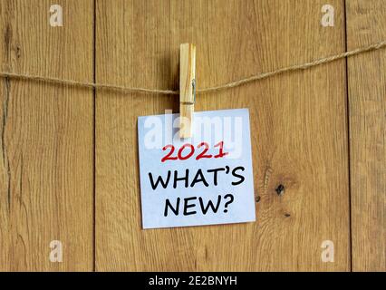 2021 what is new symbol. White sheet of paper on wooden clothespin. Words '2021 what is new'. Beautiful wooden background. Business and 2021 what is n Stock Photo