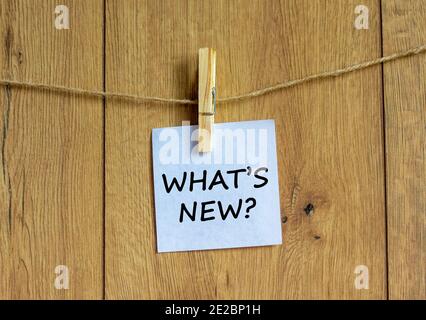 What is new symbol. White sheet of paper on wooden clothespin. Words 'what is new'. Beautiful wooden background. Business and what is new concept, cop Stock Photo