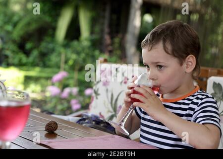 Boy drinking juice at table in cafe Stock Photo